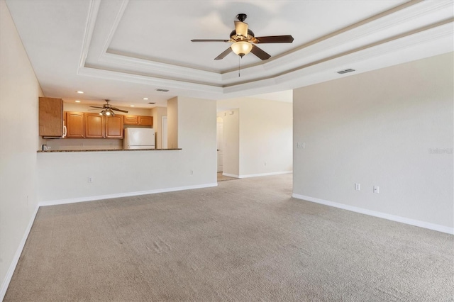 unfurnished living room featuring light carpet, ceiling fan, and a tray ceiling