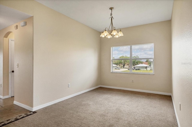 carpeted empty room featuring a notable chandelier