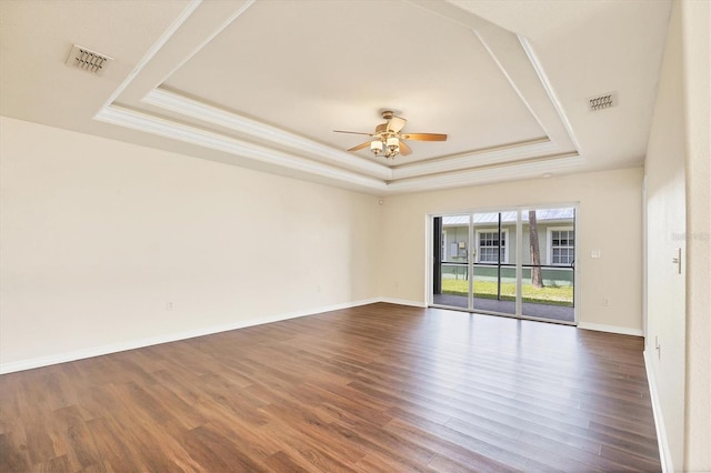 empty room with ceiling fan, a raised ceiling, and dark hardwood / wood-style flooring