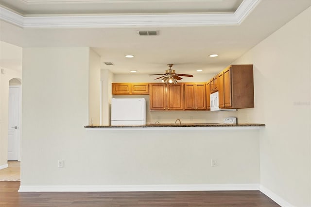 kitchen featuring ceiling fan, white appliances, light hardwood / wood-style flooring, dark stone counters, and ornamental molding