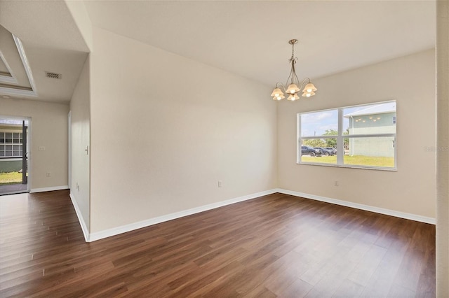 empty room featuring a chandelier and dark wood-type flooring