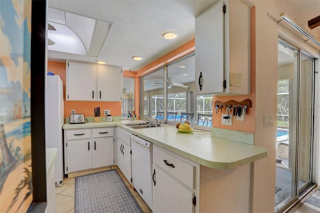 kitchen with white cabinets, sink, white appliances, and light tile patterned floors