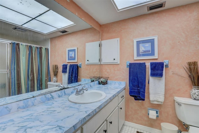 bathroom with tile patterned floors, vanity, a skylight, and toilet