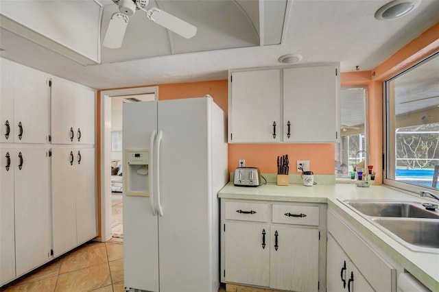 kitchen featuring white cabinets, sink, light tile patterned flooring, ceiling fan, and white fridge with ice dispenser