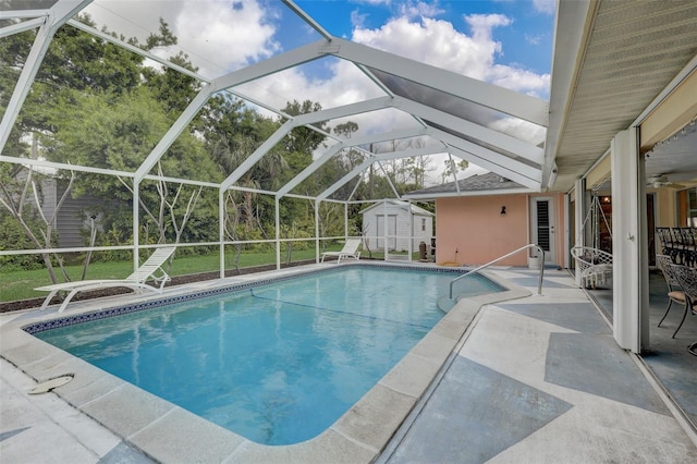 view of pool with a lanai, a storage shed, a patio, and ceiling fan