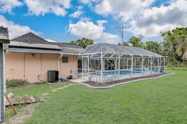 back of property with cooling unit, a patio area, a lawn, and glass enclosure