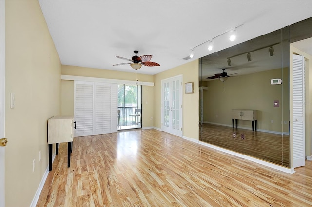 empty room featuring light hardwood / wood-style flooring, ceiling fan, and track lighting