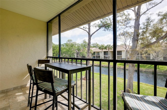 sunroom featuring a water view