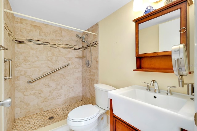 bathroom featuring large vanity, toilet, and a tile shower