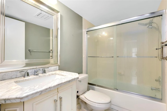 full bathroom with enclosed tub / shower combo, toilet, and vanity with extensive cabinet space