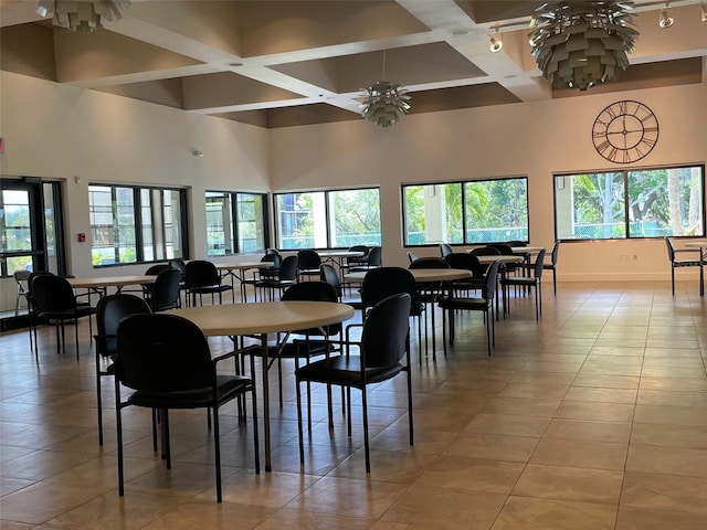 tiled dining space featuring coffered ceiling, a healthy amount of sunlight, ceiling fan with notable chandelier, and beam ceiling