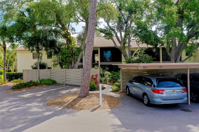 view of front of home featuring covered parking, stucco siding, and fence