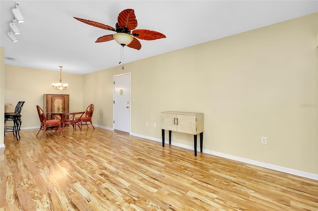 living room with visible vents, baseboards, ceiling fan with notable chandelier, and light wood finished floors