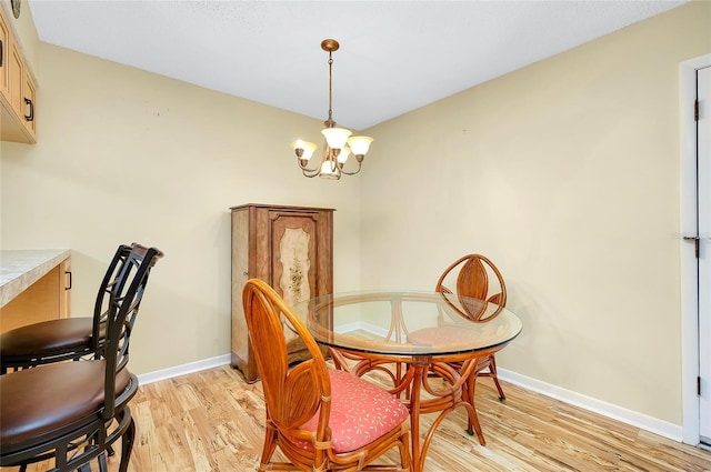 dining space with light wood finished floors, an inviting chandelier, and baseboards