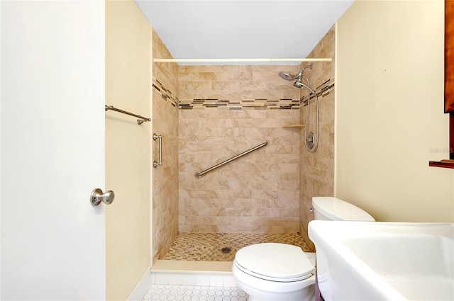 bathroom with tile patterned flooring, tiled shower, and toilet