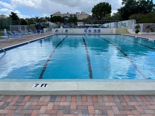 pool with a patio area and fence
