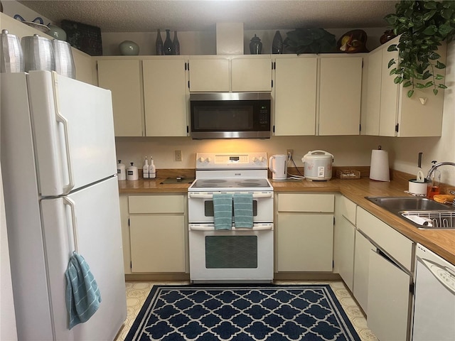 kitchen featuring white appliances, sink, and light tile floors