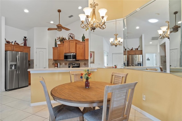 tiled dining space with ceiling fan with notable chandelier and a towering ceiling