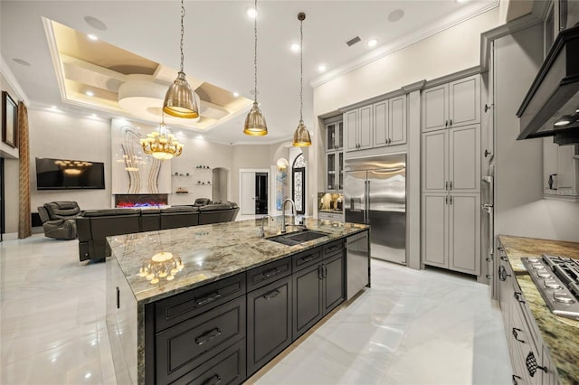 kitchen featuring sink, decorative light fixtures, wall chimney exhaust hood, a large island, and stainless steel appliances