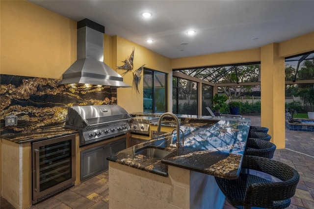 view of patio / terrace with grilling area, sink, wine cooler, a lanai, and exterior kitchen