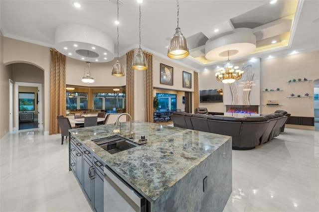 kitchen with stone counters, a large island, sink, a high ceiling, and decorative light fixtures