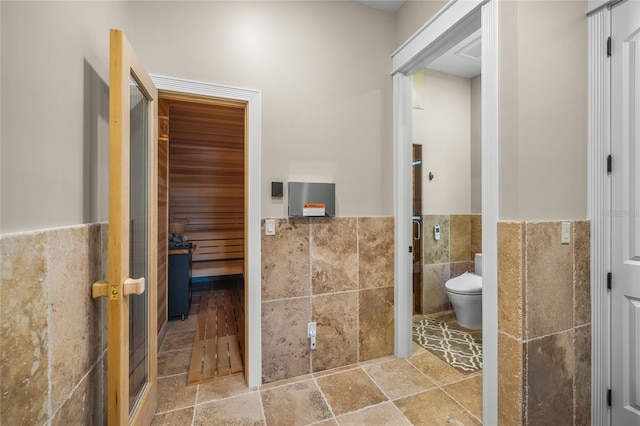 bathroom with toilet and tile walls