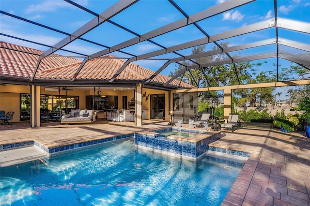 view of pool with an in ground hot tub, a patio, glass enclosure, and ceiling fan