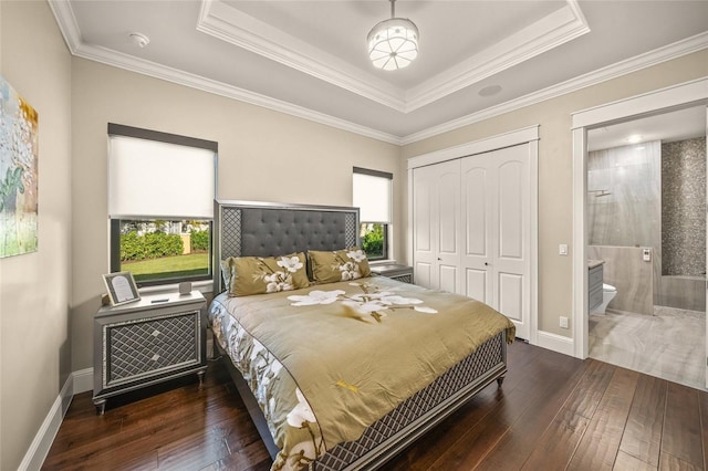 bedroom featuring a tray ceiling, connected bathroom, crown molding, and dark hardwood / wood-style floors