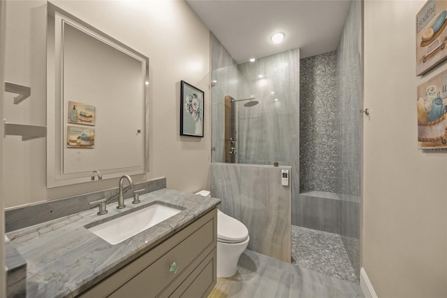 bathroom with vanity, toilet, and tiled shower