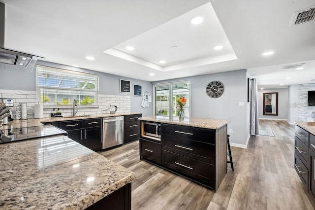 kitchen with appliances with stainless steel finishes, a center island, backsplash, and a wealth of natural light