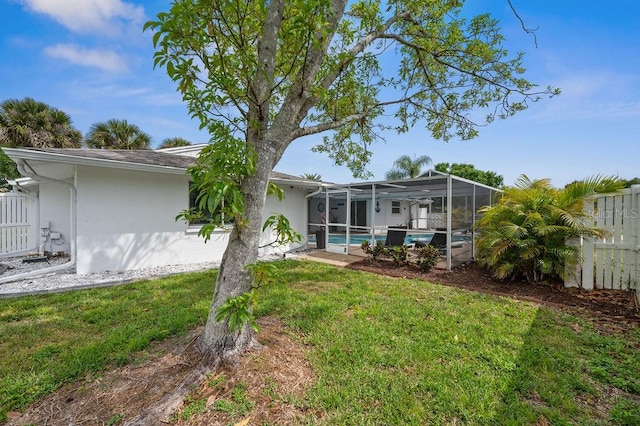 rear view of property featuring glass enclosure and a yard