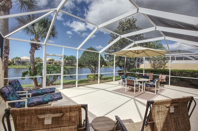 view of patio featuring glass enclosure and a water view