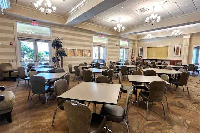 dining area featuring a raised ceiling, crown molding, a chandelier, and french doors