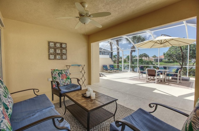 view of patio featuring a water view, ceiling fan, and glass enclosure