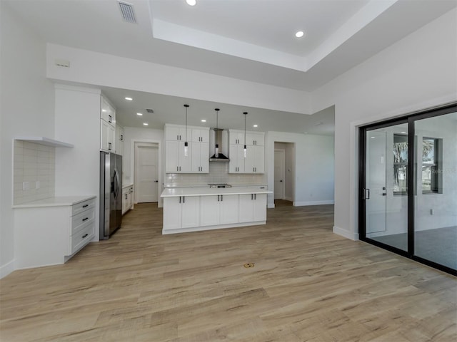 kitchen with light hardwood / wood-style floors, tasteful backsplash, white cabinets, a tray ceiling, and stainless steel refrigerator with ice dispenser