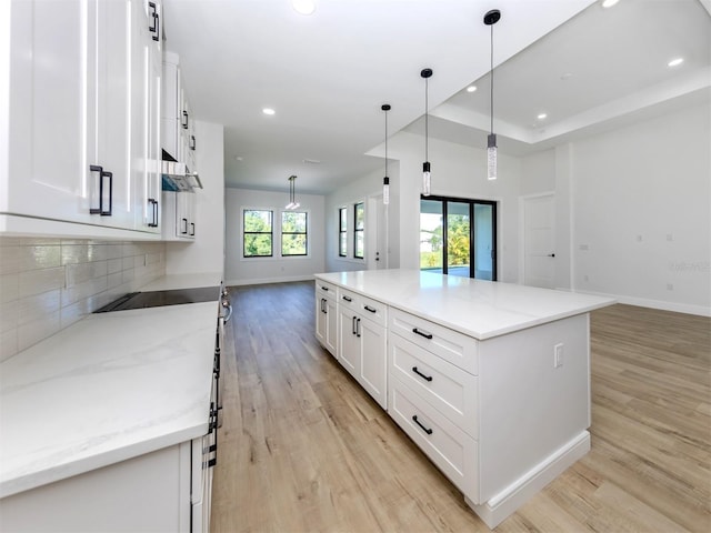 kitchen with hanging light fixtures, a tray ceiling, light hardwood / wood-style flooring, white cabinets, and a kitchen island