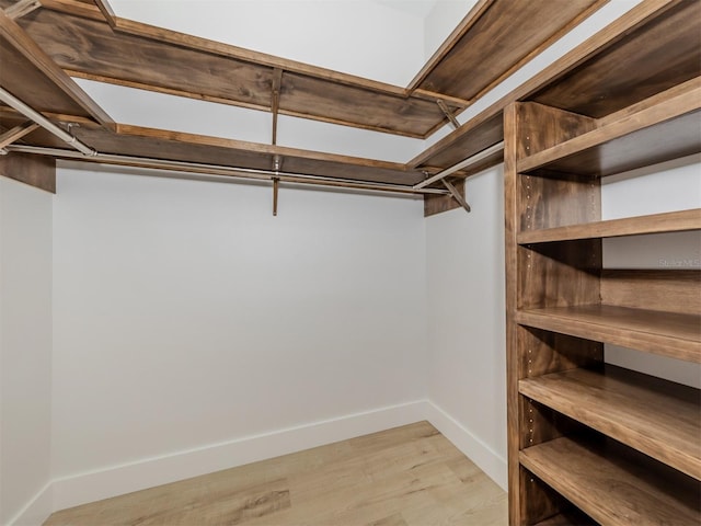 walk in closet with light hardwood / wood-style floors