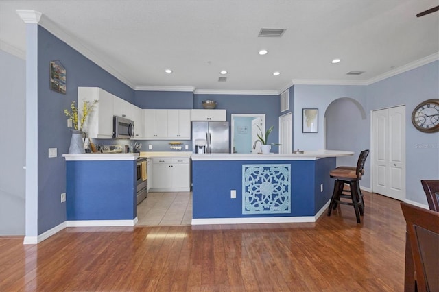 kitchen with an island with sink, appliances with stainless steel finishes, a breakfast bar, and wood-type flooring