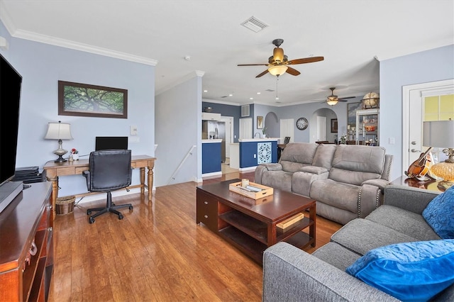 living room featuring ceiling fan, ornamental molding, and light wood-type flooring