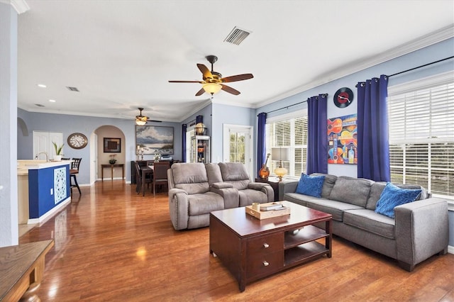 living room with ceiling fan, crown molding, dark wood-type flooring, and sink