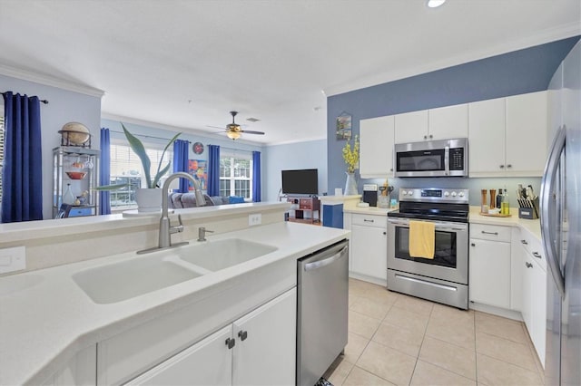 kitchen featuring appliances with stainless steel finishes, white cabinets, light tile floors, ceiling fan, and sink