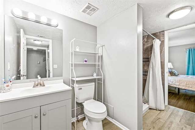 bathroom featuring toilet, a shower with shower curtain, vanity, hardwood / wood-style flooring, and a textured ceiling