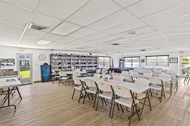 dining space featuring a drop ceiling, light hardwood / wood-style floors, and plenty of natural light