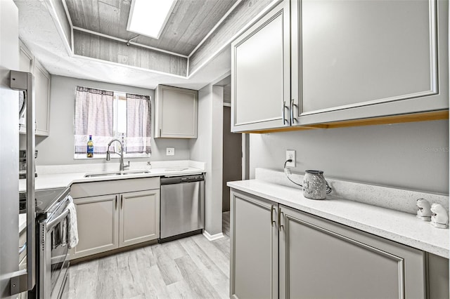 kitchen featuring sink, dishwasher, light hardwood / wood-style floors, range, and gray cabinets