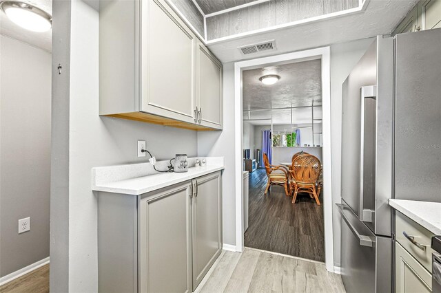 kitchen featuring stainless steel refrigerator, gray cabinets, and light hardwood / wood-style flooring