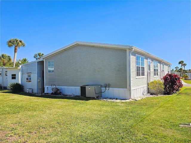 view of side of property with a lawn and central AC unit