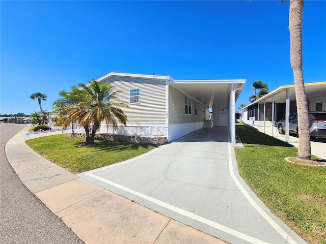 manufactured / mobile home featuring a carport and a front lawn