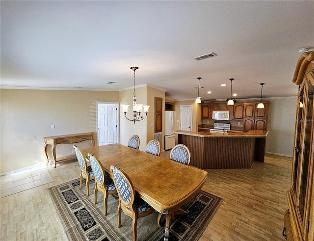 dining room featuring ornamental molding, light hardwood / wood-style floors, and an inviting chandelier