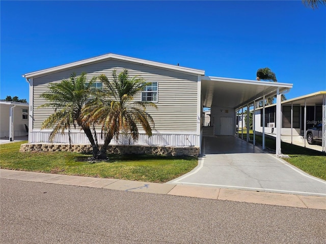 manufactured / mobile home featuring a front yard, a carport, and a sunroom