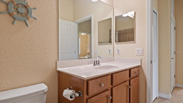 bathroom featuring tile floors, vanity, and toilet